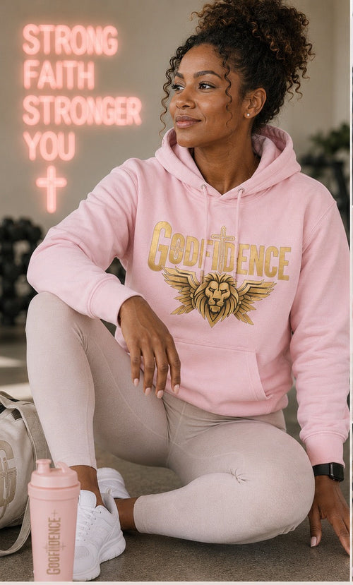Woman wearing a pink 'Goodvidence' hoodie with gold text, sitting in a gym setting.